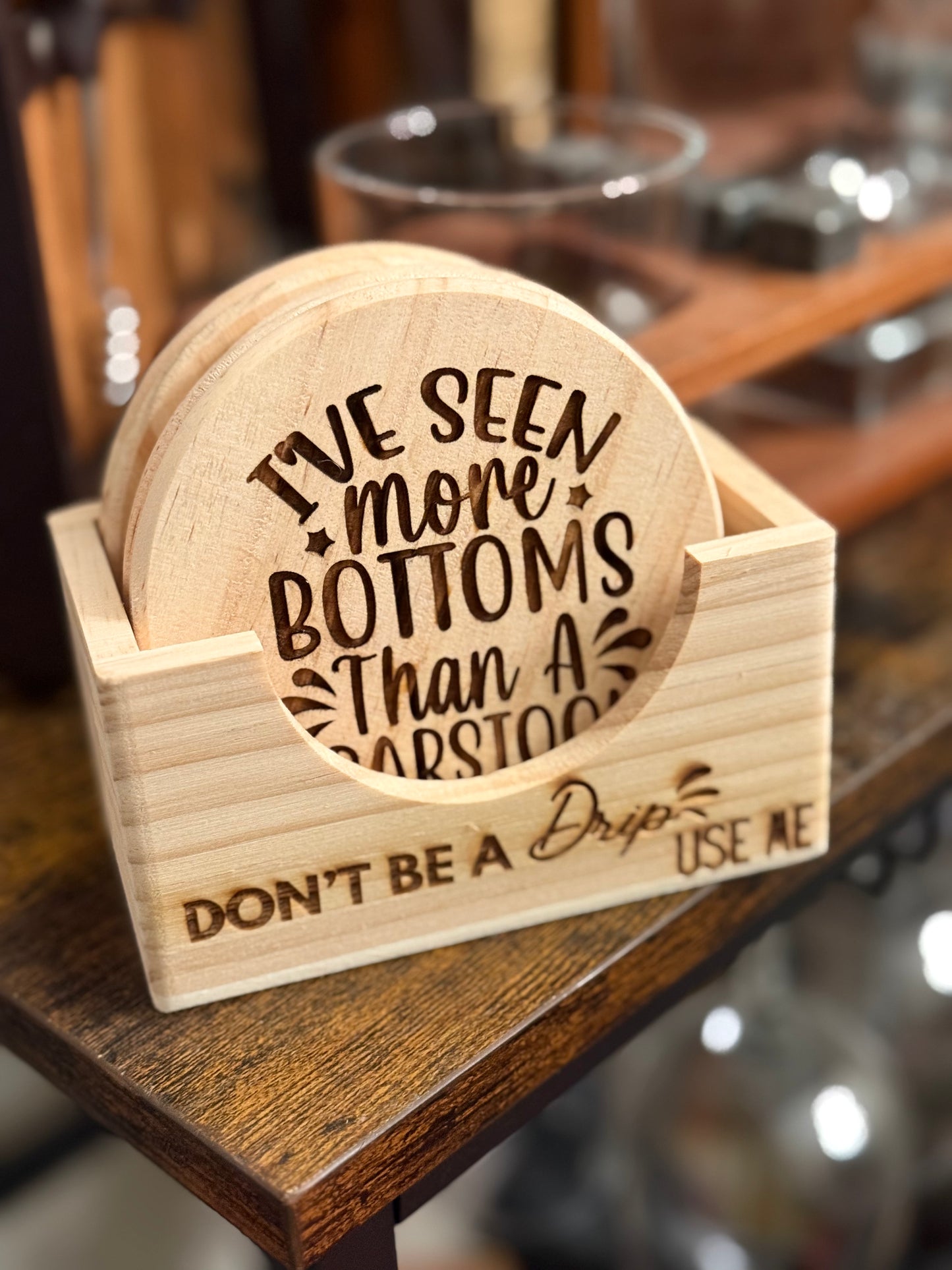 Set of six round wooden coasters engraved with funny and naughty drink sayings displayed together.