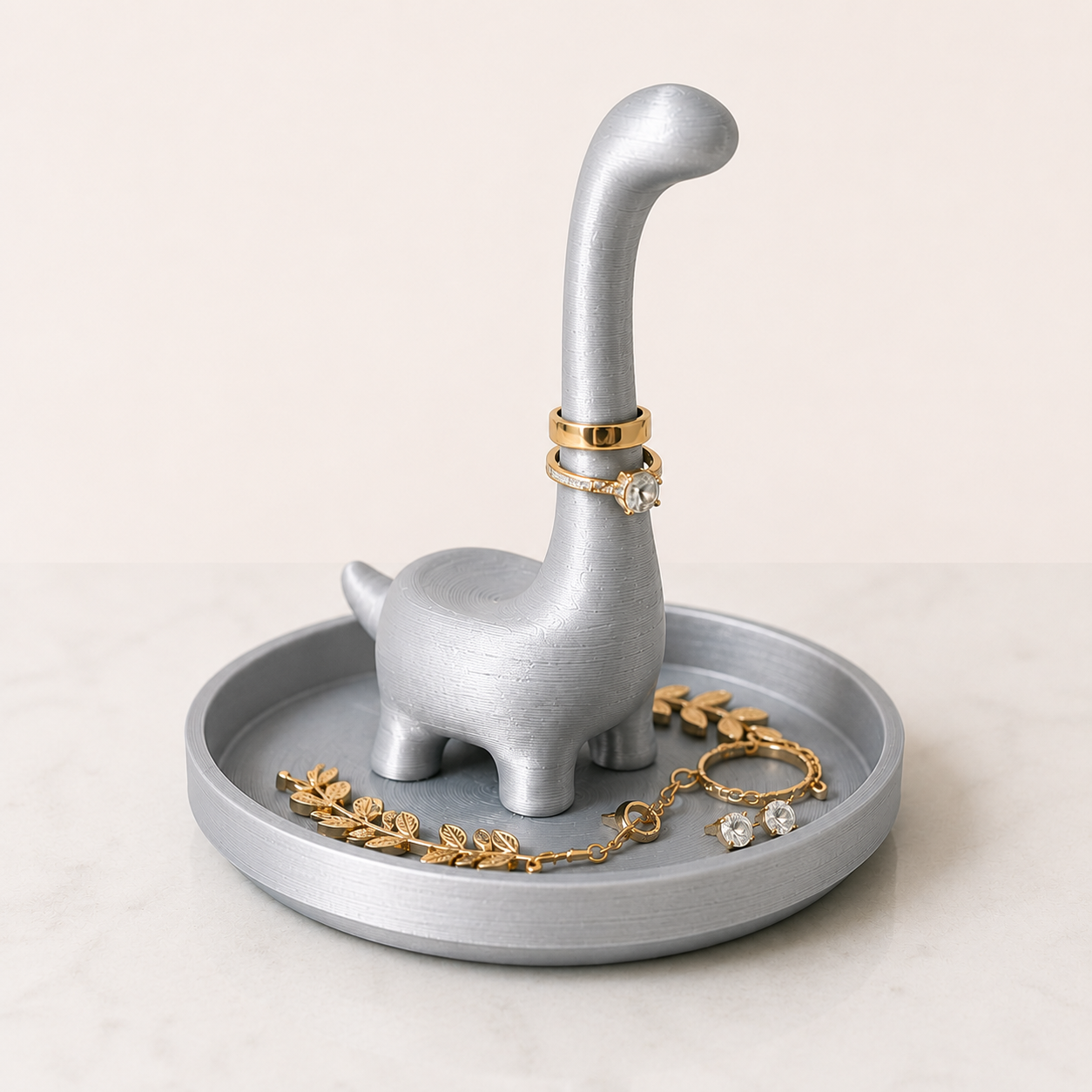 Silver 3D printed Ringosaurus dinosaur ring holder with built-in jewelry tray holding rings and small accessories
