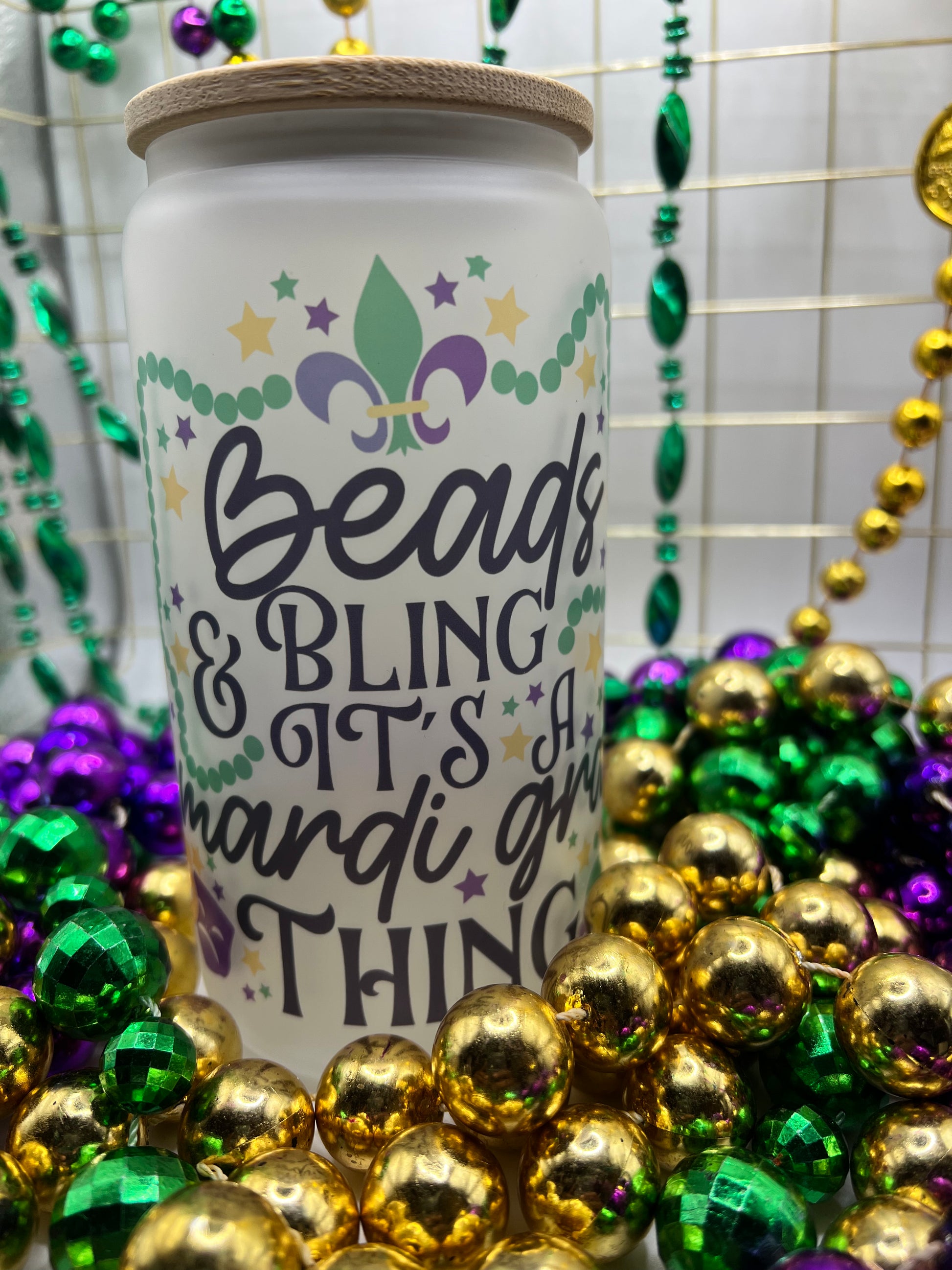 Celebrate Mardi Gras in style with our Frosted Glass Can featuring the lively slogan 'Beads, Bling, It's a Mardi Gras Thing.' Includes a Bamboo Lid and Straw for a festive touch. Perfect for sipping in vibrant fashion and making a statement at your lively celebration!